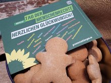 Plätzchen in Menschenform in einer Schale mit der Postkarte zum Tag der Menschenrechte