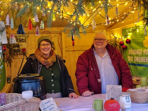 Zwei Personen stehen in einer Holzbude und verkaufen Kürbissuppe