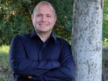 GRÜNER Landratskandidat Felix Senner lehnt im blauen Hemd an einem Baum
